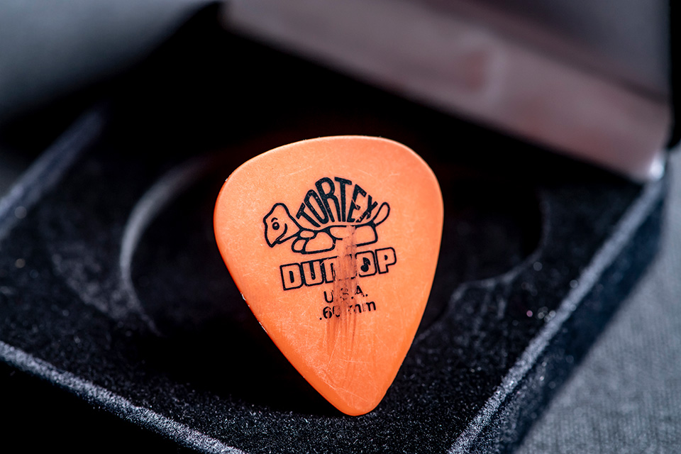 An orange plectrum with marks on it, inside a black casetest